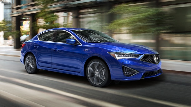 A blue Acura ILX driving down the city streets during the day time. 