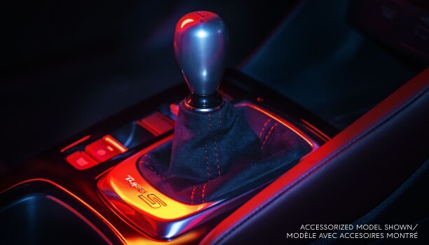 Closeup of gear shifter, dimly lit with red light. 