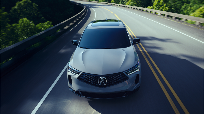 Plan de trois quarts en plongée d’un RDX gris circulant sur l’autoroute par une journée ensoleillée.