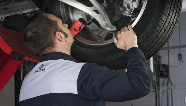 Closeup of Acura Technician inspecting the disc brake on an Acura.