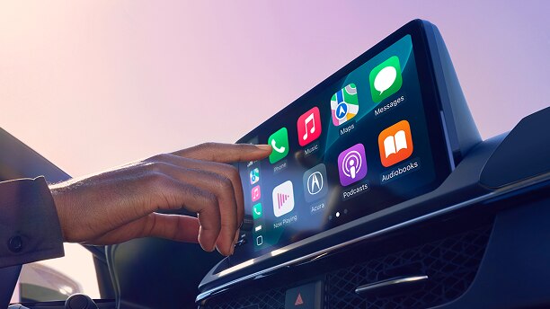 Gros plan d’une main utilisant la technologie Google intégrée sur l’écran du tableau de bord. 