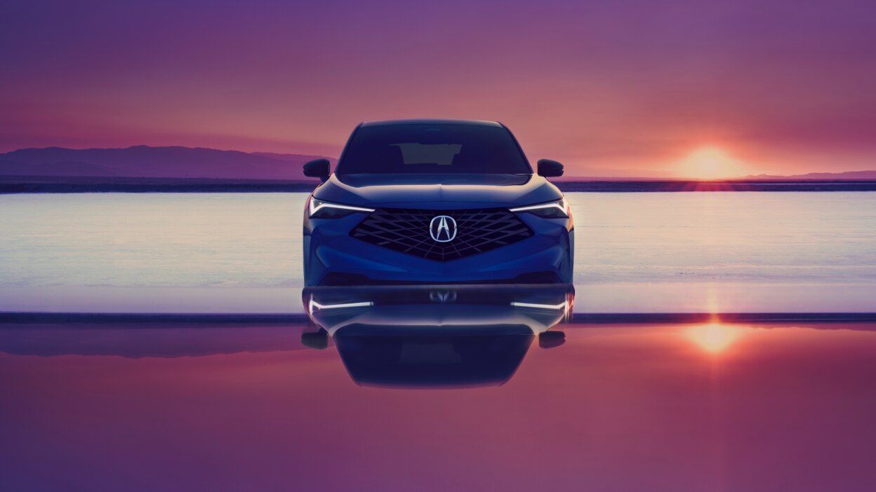 Acura ADX bleu vu de face avec un coucher de soleil en arrière-plan.
