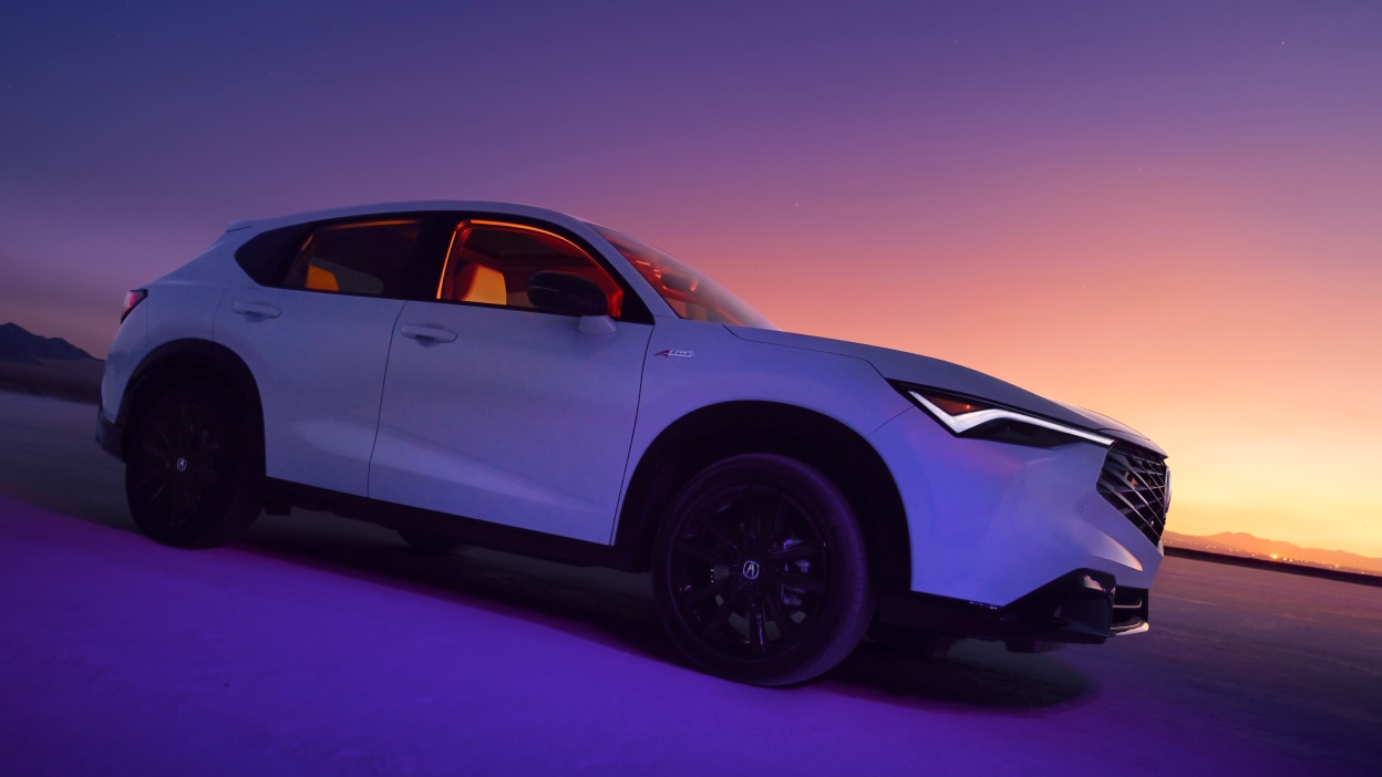 Acura ADX blanc vu de côté avec un coucher de soleil au loin.