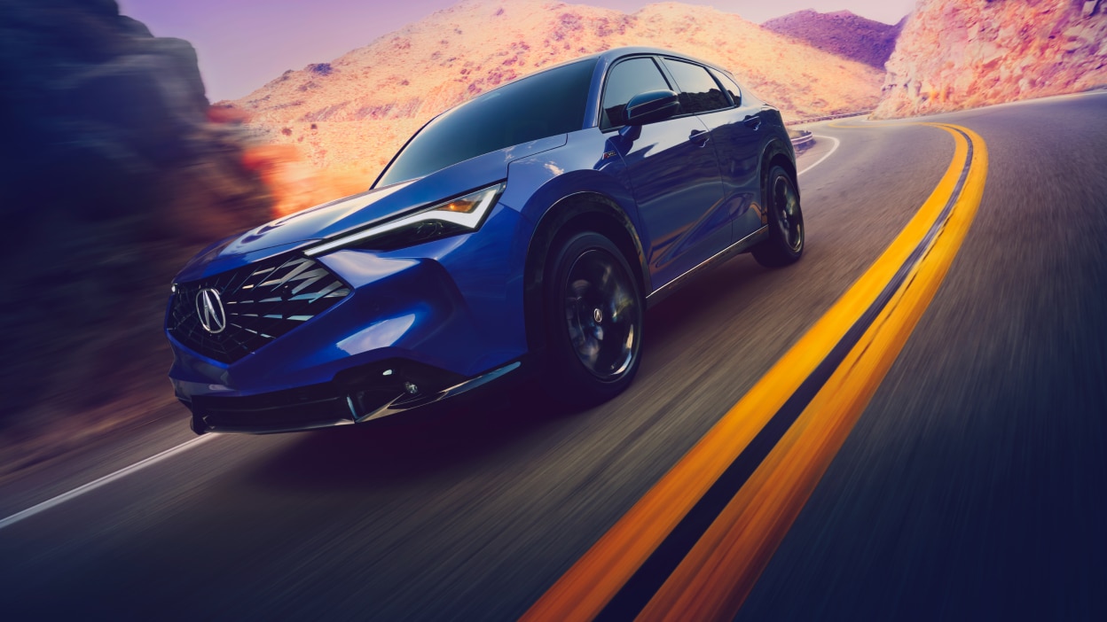 Acura ADX vu de côté tournant sur une autoroute montagneuse.