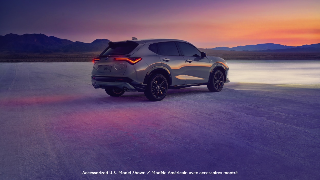 Wide rear-view shot of an Acura ADX with a dusky sunset in the background.