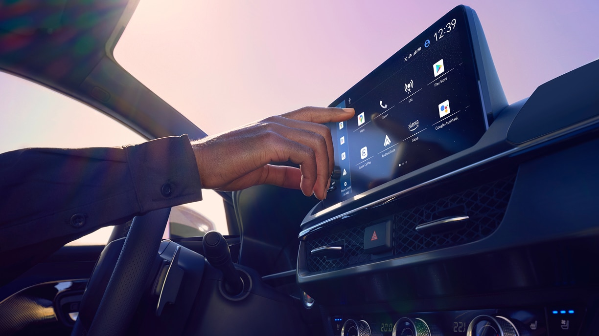 Gros plan d’une main utilisant la technologie Google intégrée sur l’écran du tableau de bord.