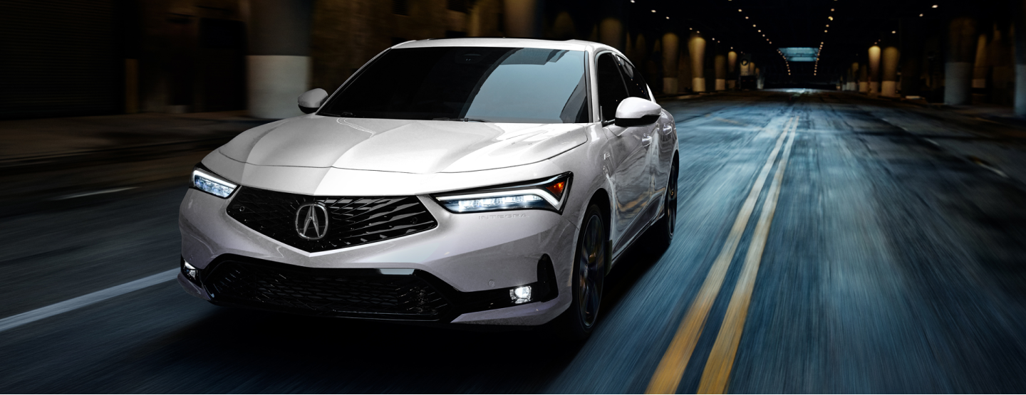 3/4 front view of white Integra driving in an empty underground expressway. 