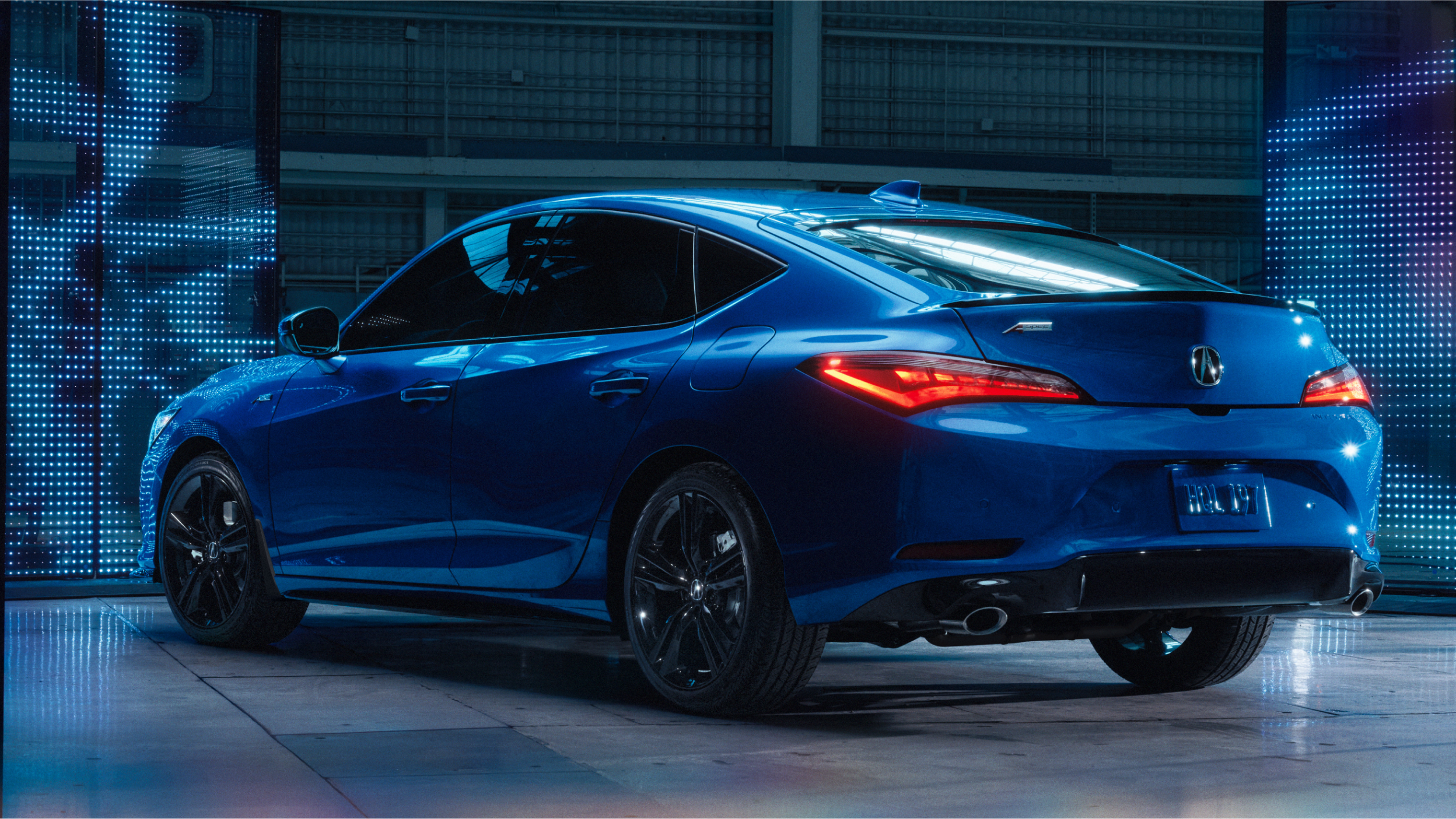 Close-up of 2023 Integra frameless front grill with illuminated Acura badge in dark background