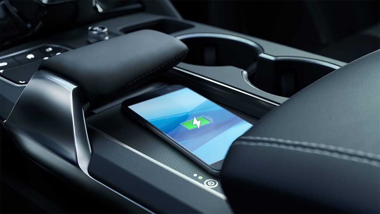 A smartphone on a wireless charger between the two front seats.