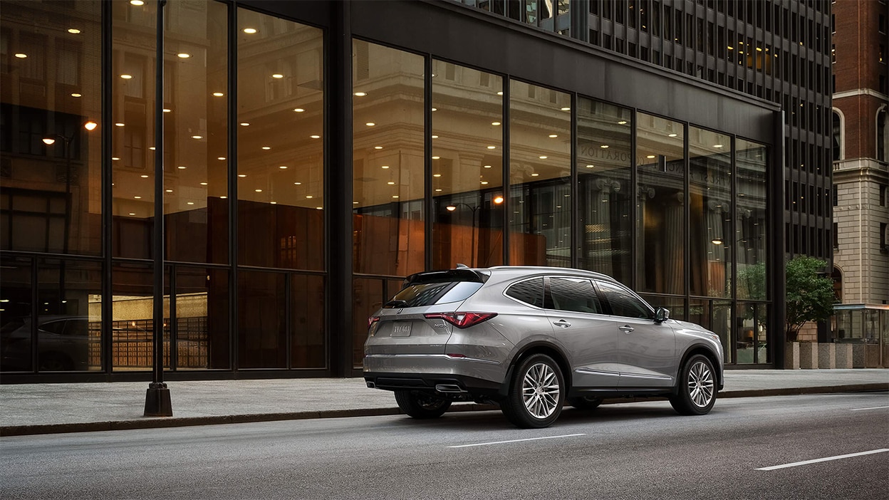A grey Acura Acura MDX parked on a city street.