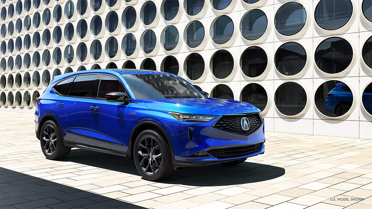 A blue Acura MDX parked outside a building with artistic architecture