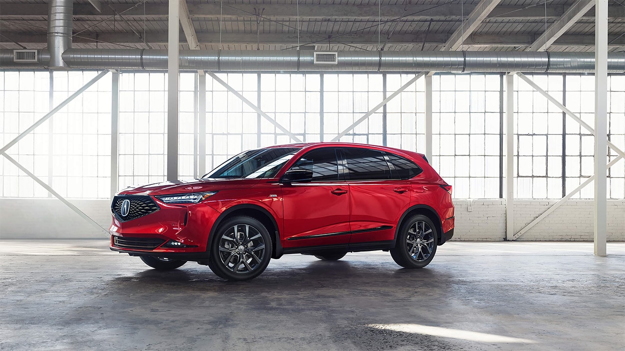 A red Acura MDX parked inside a bright, spacious warehouse.
