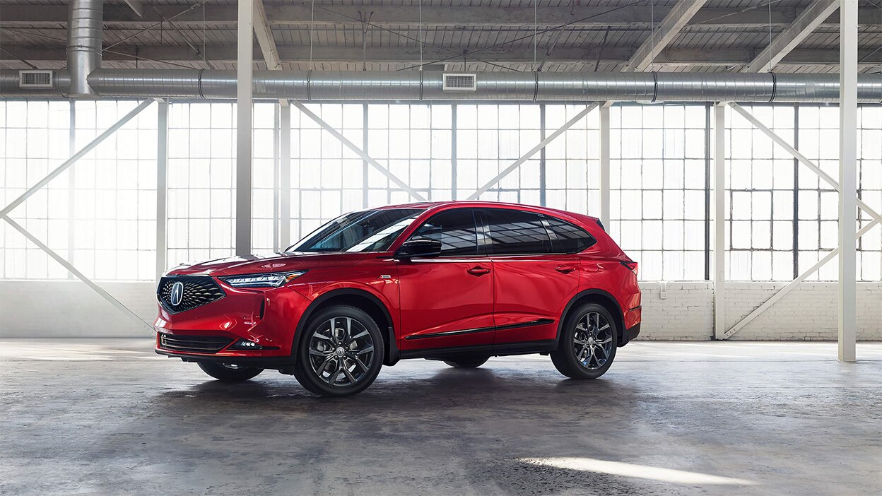 A red MDX parked inside a bright, spacious warehouse.