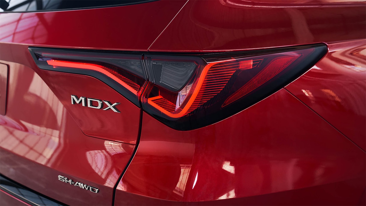 The tail light of a red Acura MDX.