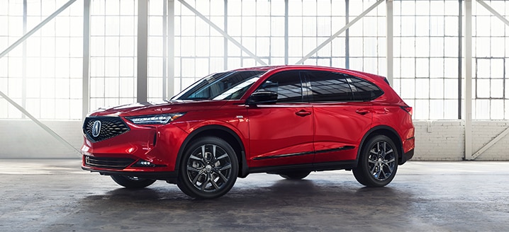 Side view of a red Acura MDX in a bright, spacious warehouse / Vue latérale d’un MDX rouge dans un entrepôt spacieux et lumineux