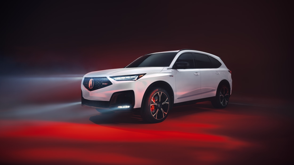 Un MDX rouge emprunte une route en pleine nature.