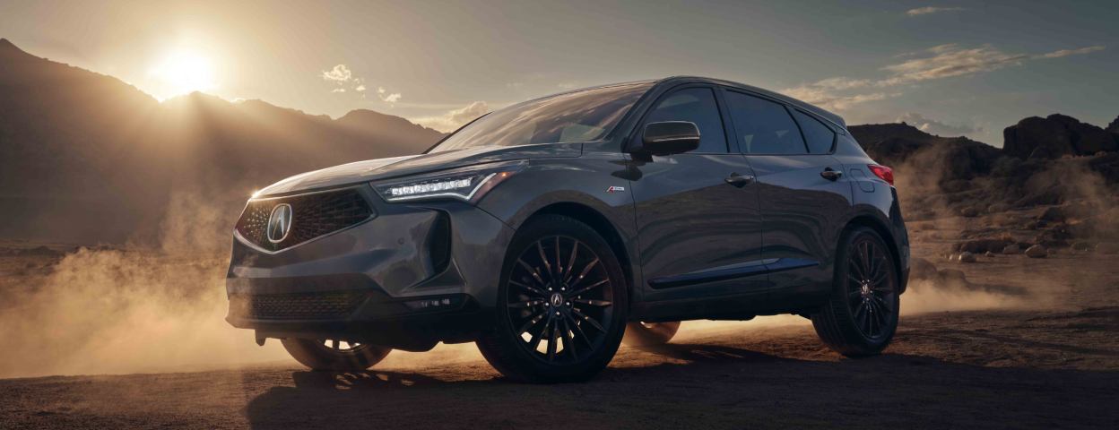 3/4 profile view of Acura RDX in desert, with a low sun behind it. 