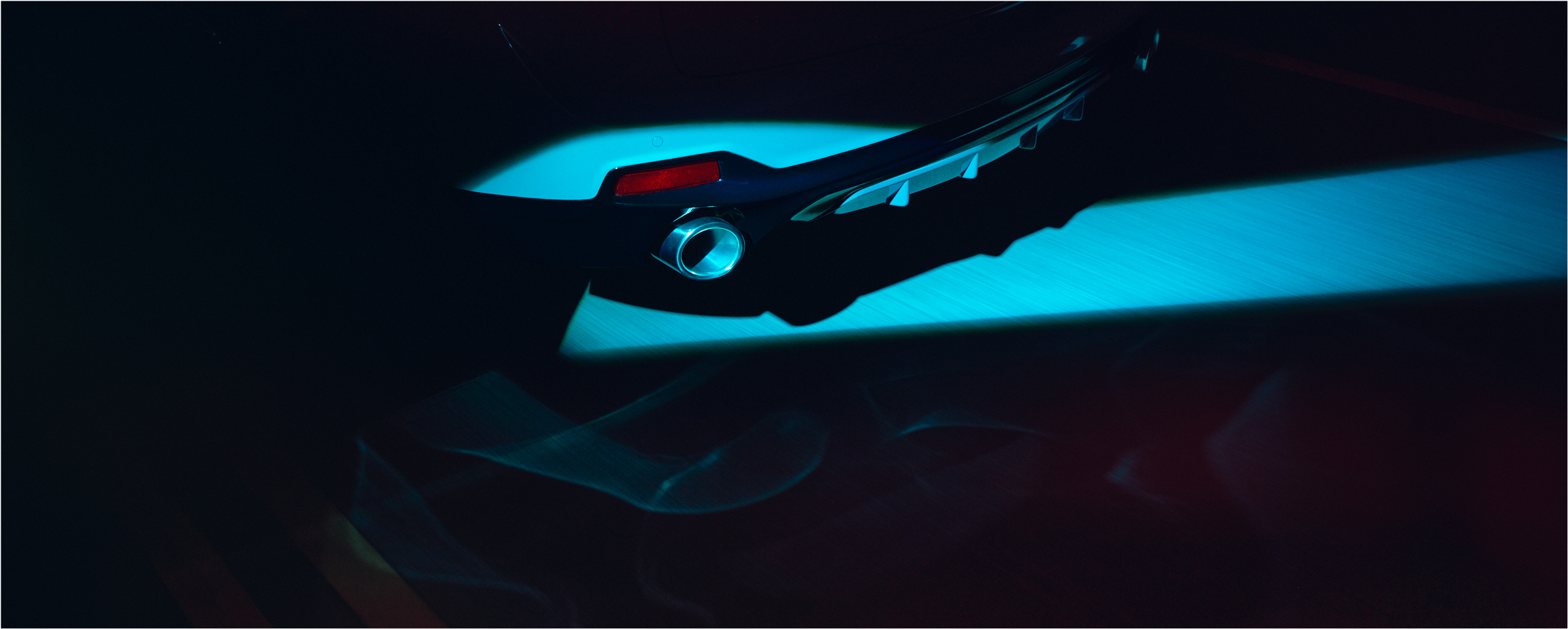 3/4 rear view of RDX driving at night. Tailpipe exhaust finisher is showcased by a spotlight.