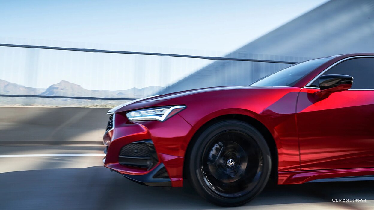 Side view of a red TLX driving over a bridge.