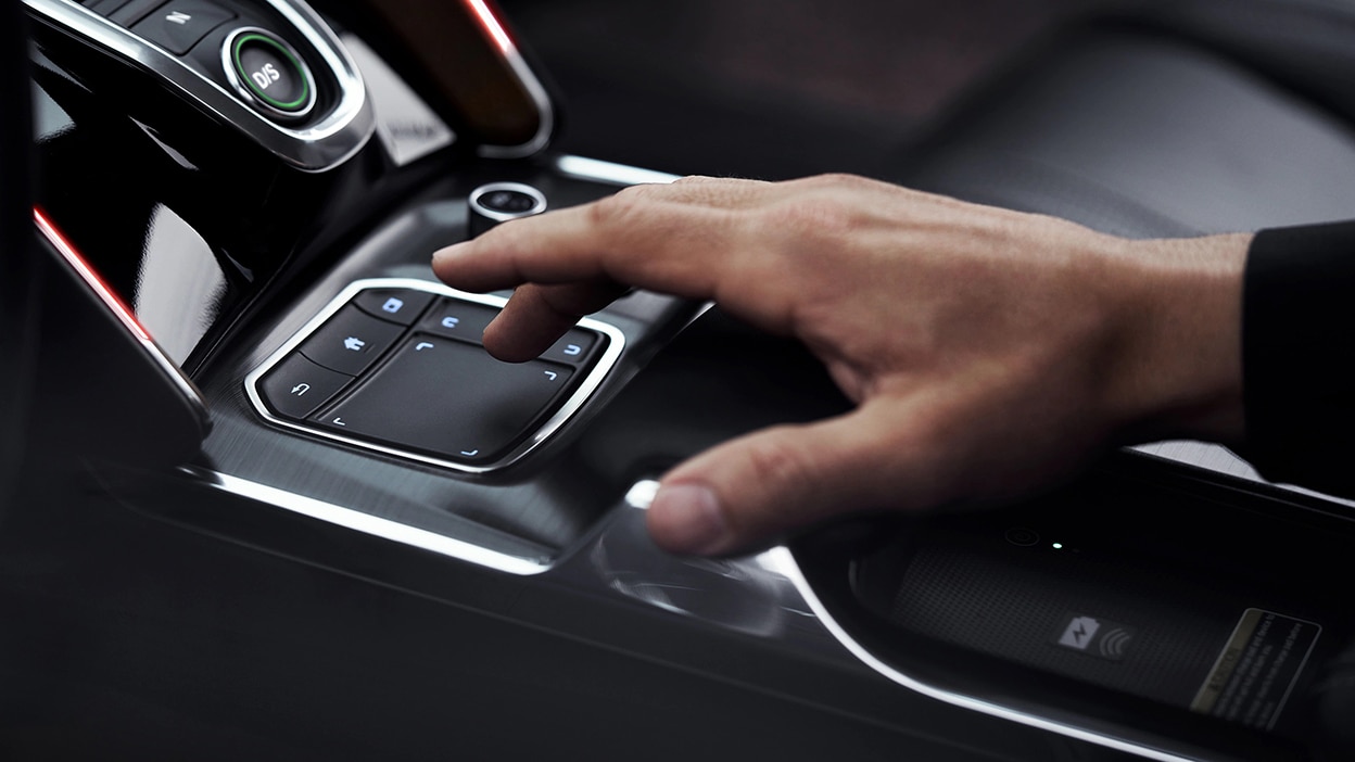 A hand hovers over the True Touchpad interface between the two front seats.
