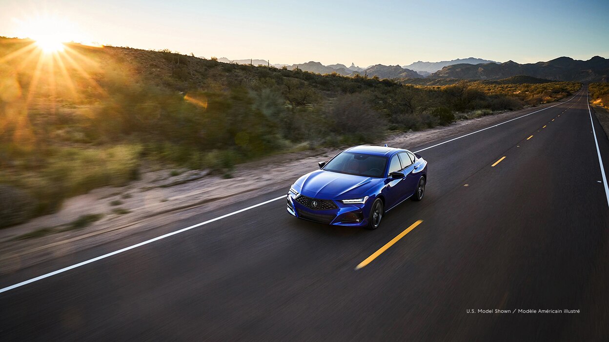 A blue Acura TLX driving down a road.