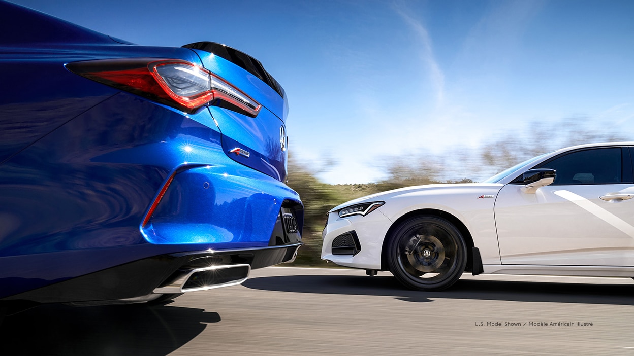 A blue Acura TLX and a white TLX driving beside each other.