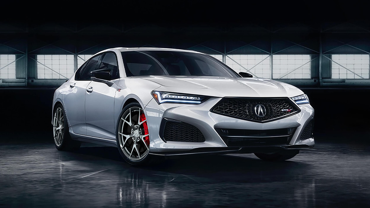 A white TLX in a darkly-lit warehouse.