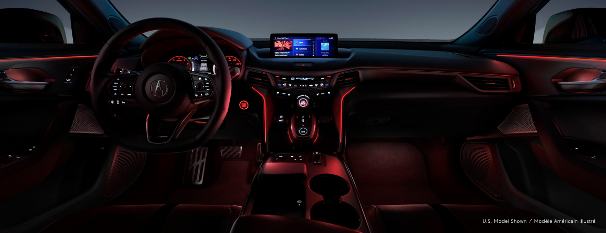 The cockpit of a TLX with red mood lighting. / Habitacle d’une TLX avec éclairage ambiant rouge.