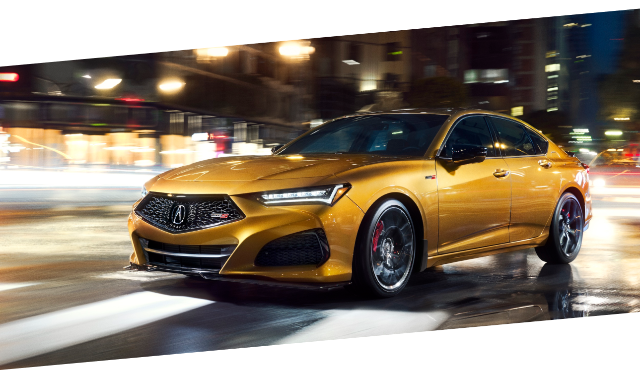 A gold Acura TLX Type S driving on a city street at night. / TLX Type S de couleur or circulant sur une rue urbaine la nuit.