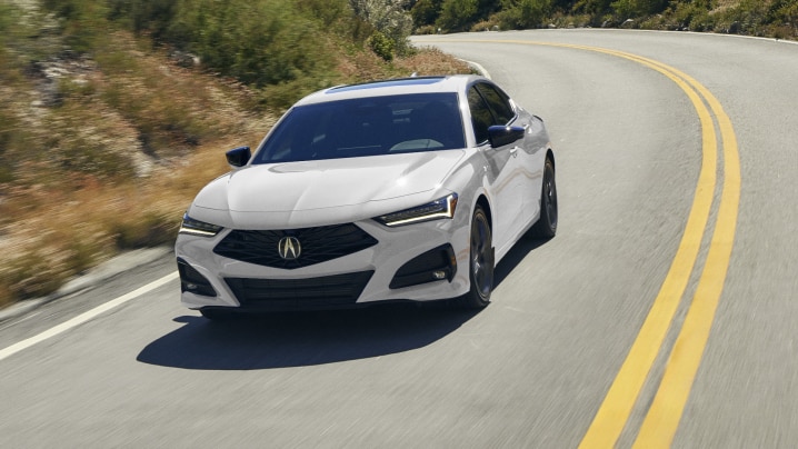 Front view of white TLX taking a turn on highway.