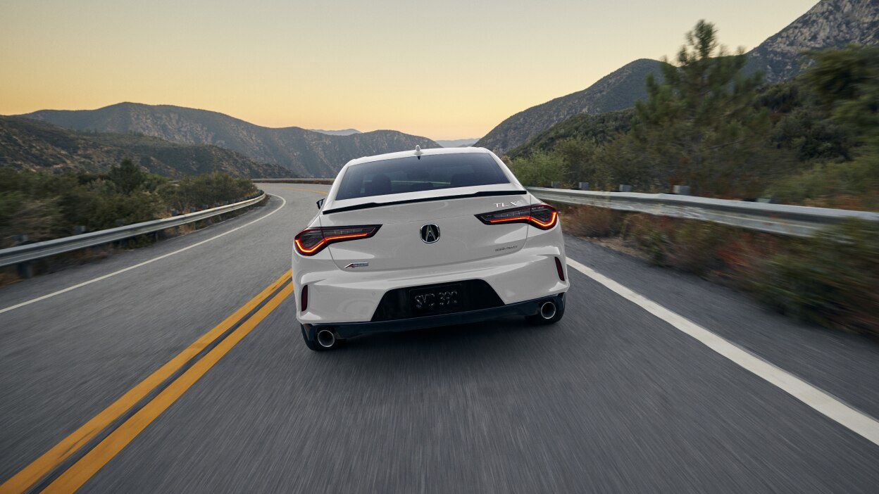 A white TLX in a darkly-lit warehouse.