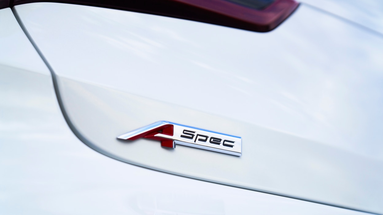 Gros plan de l’emblème A-SPEC sur le coffre d’une TLX blanche.