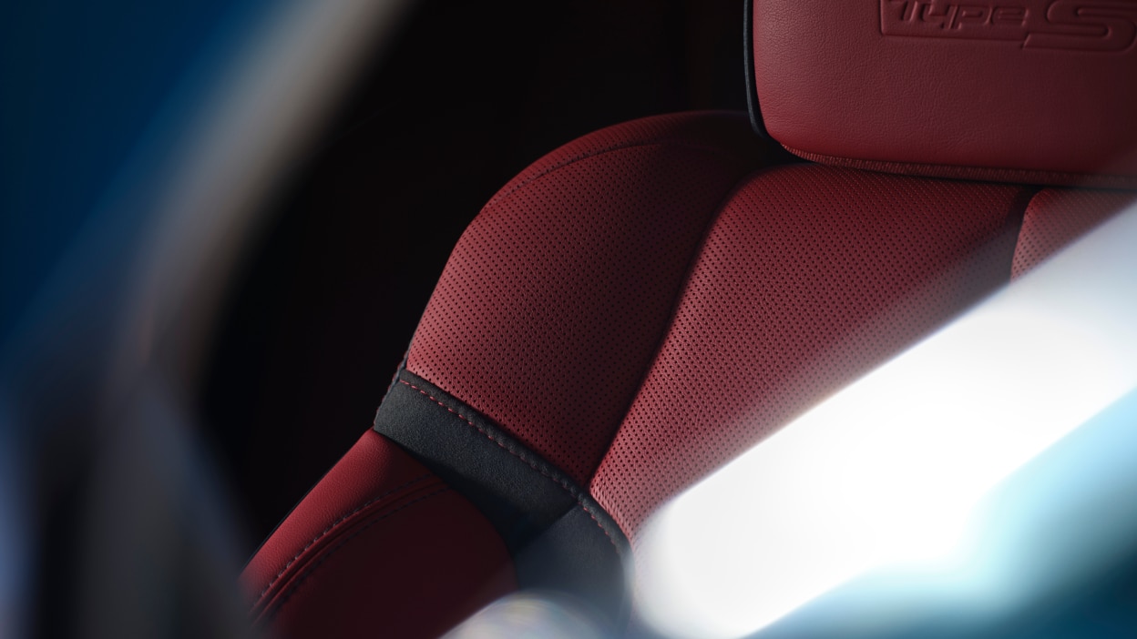 Closeup of perforated red seating surface of the driver’s seat.