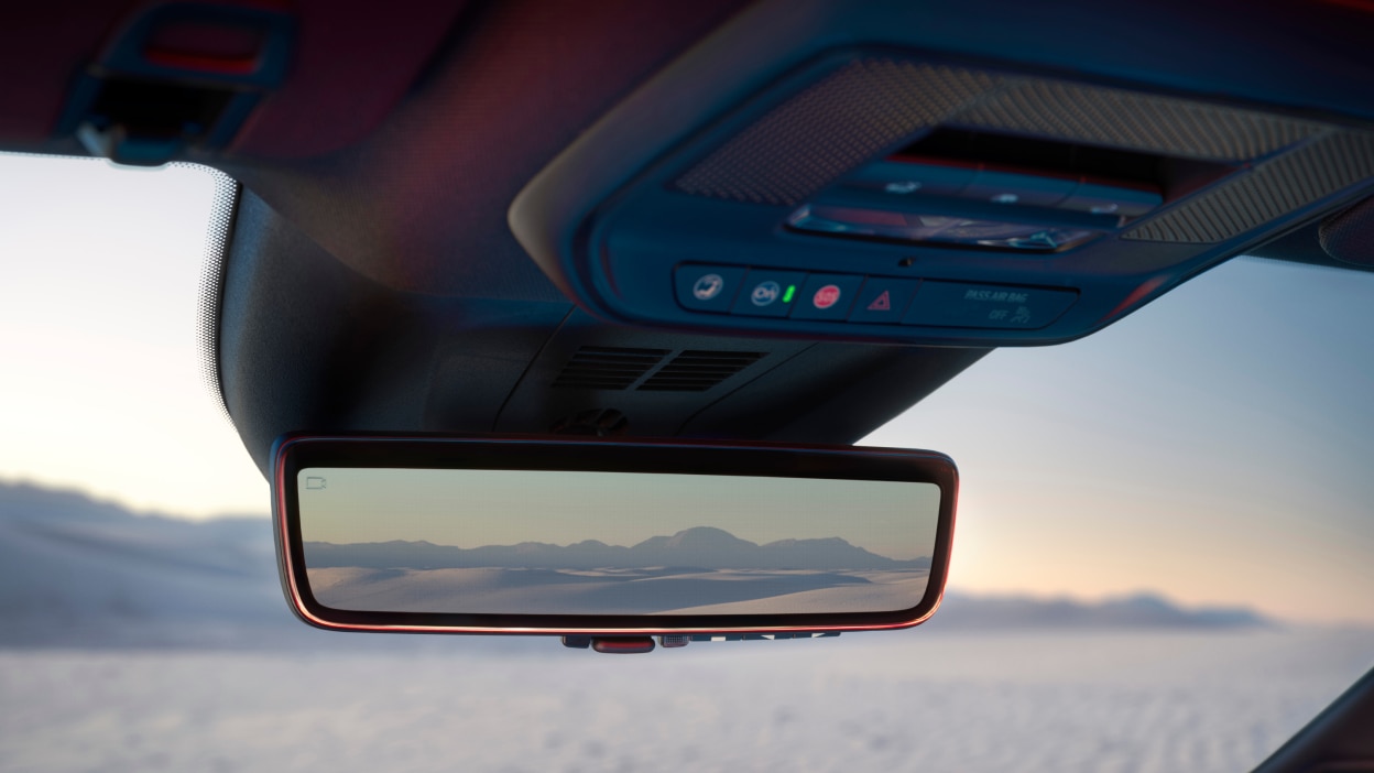 Closeup of rearview mirror, reflecting sand dunes in the distance.
