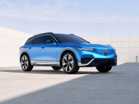 Vue 3/4 avant du ZDX bleu stationné, entouré d'une architecture moderne et minimaliste.