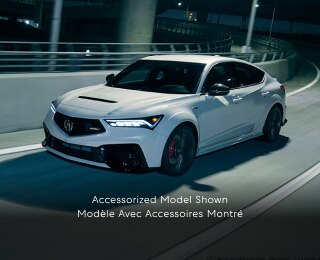 3/4 front side view of white Integra Type S taking a turn on a highway onramp at night.