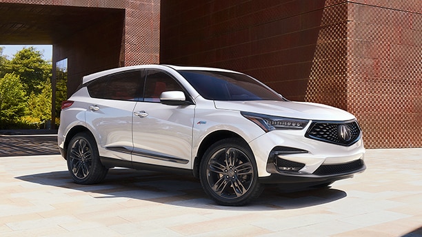 A silver RDX parked under an overpass / Un Acura RDX argent stationné sous un passage supérieur. 