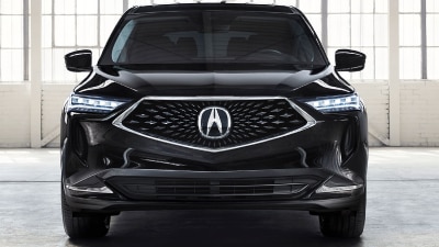 Front-facing shot of a black Acura MDX parked in a large, empty white garage space featuring loft-style windows and white brick walls.	Vue avant d’un Acura MDX noir stationné dans un grand garage blanc vide muni de fenêtres de style loft et de murs de briques blanches.