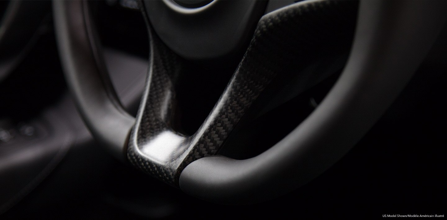 A close-up of an Acura's black leather steering wheel. / Gros plan du volant en cuir noir d’une Acura.