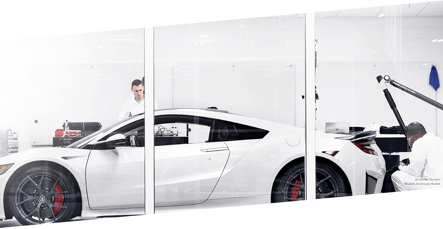 Two technicians work on a white Acura NSX at the PMC.  / Deux techniciens travaillant sur une Acura NSX blanche au PMC.