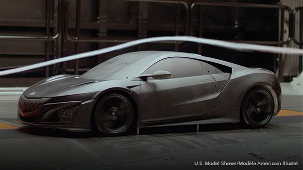 Driver side shot of a black Acura NSX Supercar in a testing garage facility. An air stream flows above as the car as it is put through a wind tunnel test. // Vue du côté conducteur d’une supervoiture Acura NSX noire dans le garage d’une installation d’essai. Un flux d’air circule au-dessus du véhicule lors d’un essai en soufflerie.