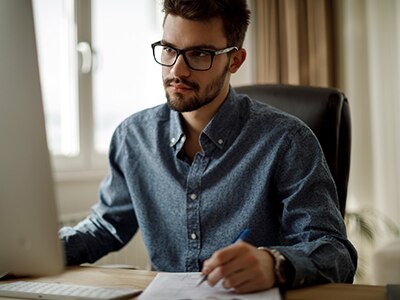 A young man works at a computer. / Un jeune homme travaille à l’ordinateur.