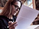 A woman wearing glasses inspects paperwork. / Une femme portant des lunettes examine un document.