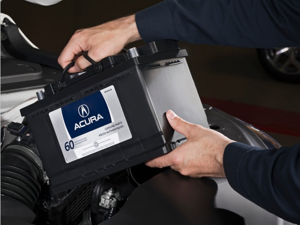 A certified Acura mechanic is installing an Acura genuine car battery. // Un mécanicien Acura certifié installe une batterie de voiture Acura d'origine