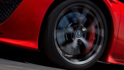 Front wheel spinning of a red NSX as it is driven on the road. // Roue avant d'une NSX rouge qui tourne en roulant sur  la route