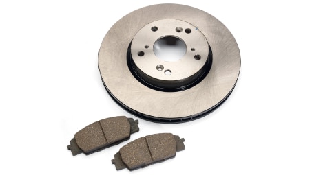 Studio shot of two brake pads and a rotor. // Une photo en studio de deux plaquettes et d’un disque de frein