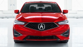 Front facing exterior shot of a red Acura ILX showcasing the Acura emblem on the front grill. // Plan extérieur de l'avant d'une Acura ILX rouge présentant l'emblème Acura sur la calandre avant