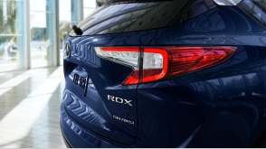 Exterior rear brake light shot of an Acura RDX parked in a vehicle showroom. // Plan de feu de frein arrière extérieur d'un Acura RDX stationné dans une salle d'exposition de véhicules