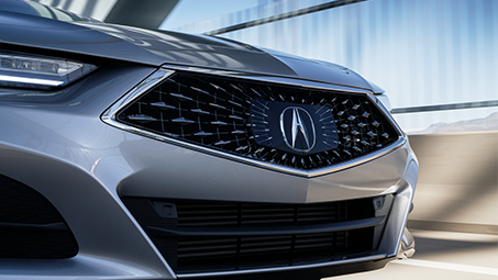 Close up view showing the front grill and headlights on a silver Acura. // Vue rapprochée montrant la grille et les phares d’une Acura grise métallisée.