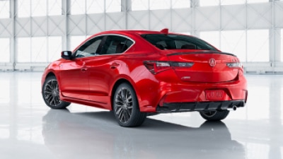 A Red ILX parked in a vehicle showroom with it’s front left wheel turned to the left. // Une ILX rouge stationnée dans une salle d'exposition de véhicules avec sa roue avant gauche tournée vers la gauche.